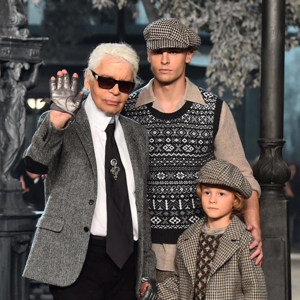 Karl Lagerfeld posiert mit zwei Models auf einem Laufsteg.