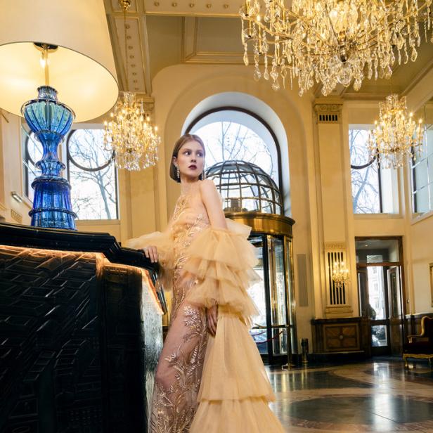 Eine Frau in einem eleganten, rüschenbesetzten Kleid in einer opulenten Hotellobby.