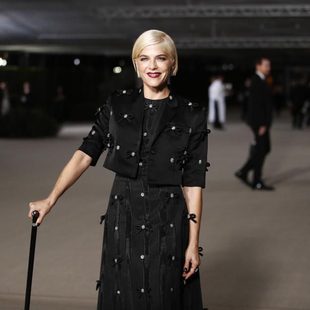 Selma Blair in einem schwarzen Kleid mit Schleifen und Gehstock auf dem roten Teppich.