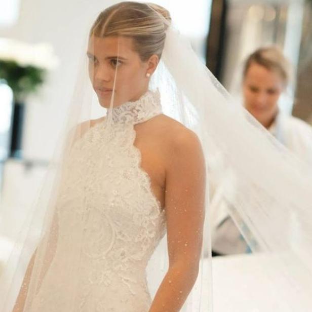 Eine Braut mit Schleier und hochgeschlossenem, weißem Kleid.