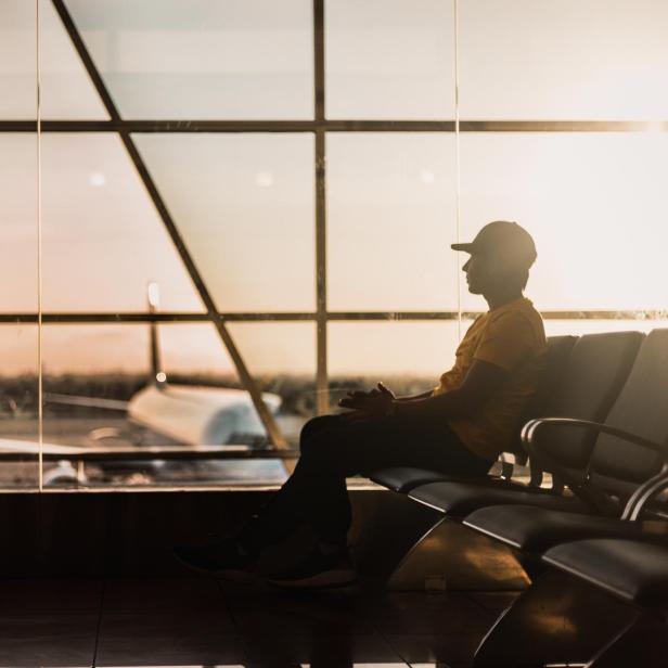 Ein Mann sitzt in einem Wartebereich am Flughafen.