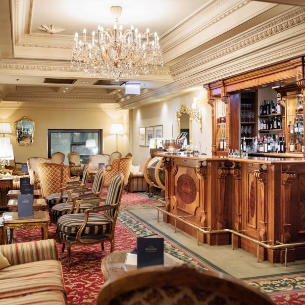 Eine elegante Hotelbar mit dunklem Holz und Kristalllüster.