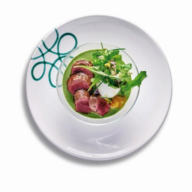 Ein Gericht mit Maibock, Salat und grüner Soße wird auf einem Teller serviert.