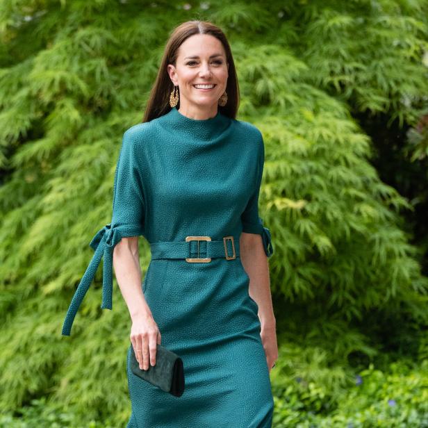 Catherine, Prinzessin von Wales, in einem grünen Kleid mit goldenen Ohrringen vor einem grünen Hintergrund.