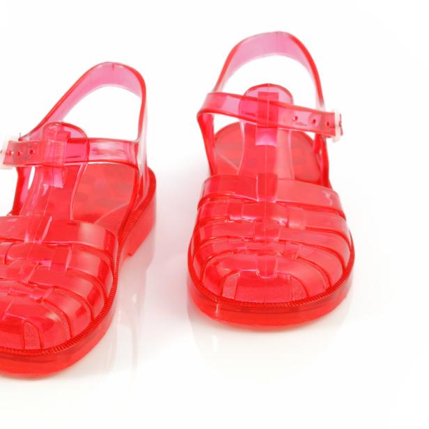 Ein Paar rote, durchsichtige Sandalen aus Kunststoff stehen auf einem weißen Hintergrund.
