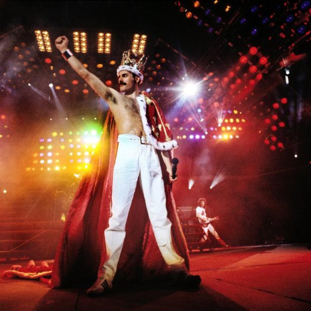 Freddie Mercury von Queen mit Krone und rotem Umhang auf der Bühne.
