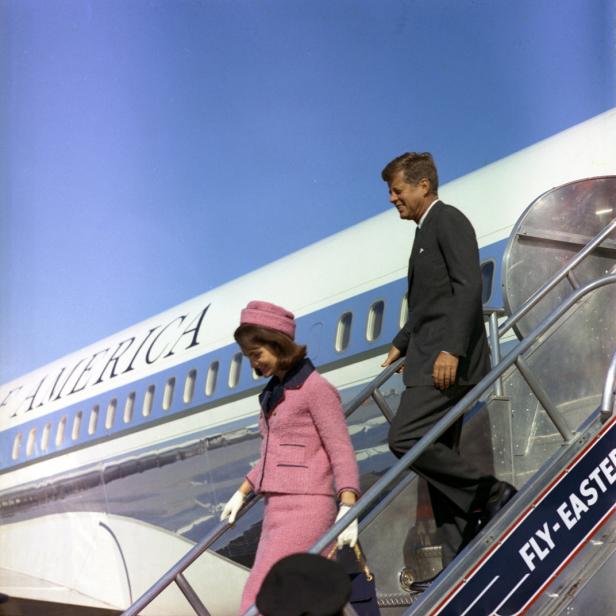 John F. Kennedy und Jackie Kennedy steigen eine Flugzeugtreppe hinunter.