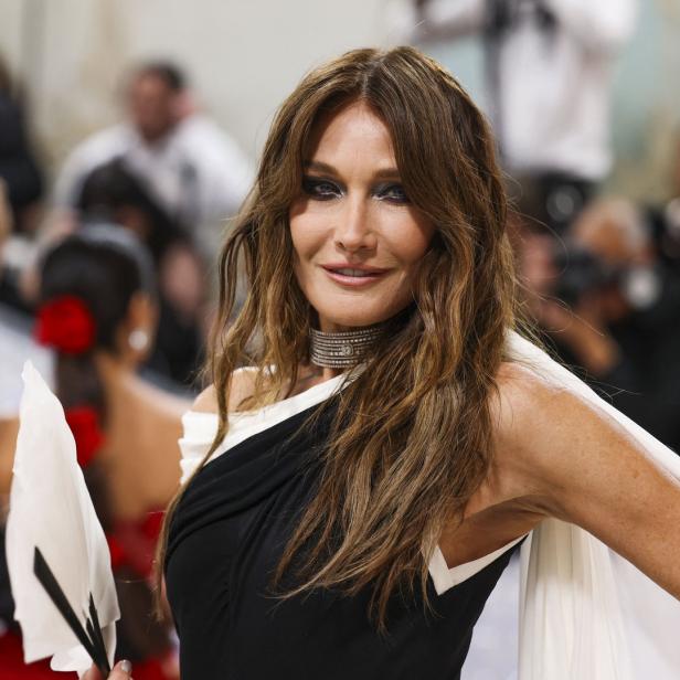 Carla Bruni trägt ein schwarz-weißes Kleid und eine Halskette.