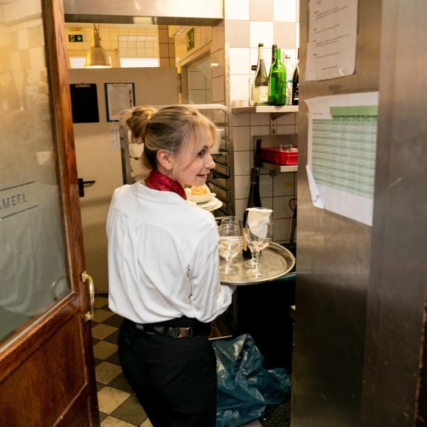 Eine Kellnerin trägt ein Tablett mit Gläsern im Restaurant „Schwarzes Kameel“ in Wien.