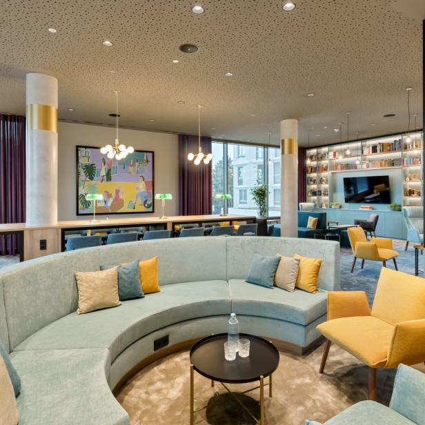 Ein modern gestalteter Aufenthaltsraum mit Sitzgelegenheiten und Bücherregalen.