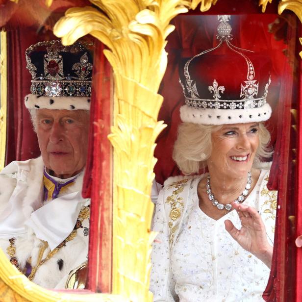 König Charles und Königin Camilla fahren in einer goldenen Kutsche.