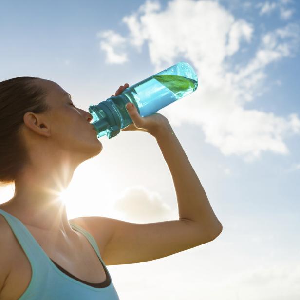 Sportliche Frau trinkt aus Flasche.
