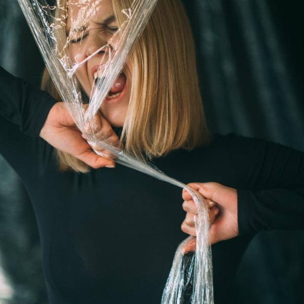 Eine Frau mit blonden Haaren kämpft mit einer Plastikfolie.