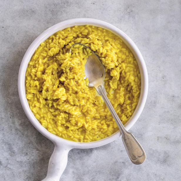 Ein Teller Risotto mit Safran und einem Löffel darauf.