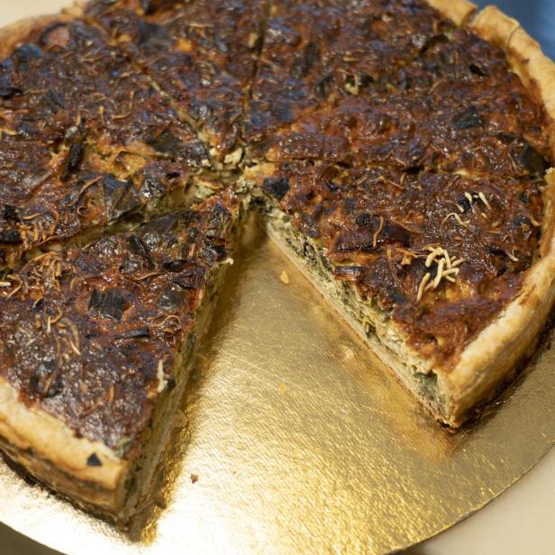 Eine Quiche mit Gemüse und Käse auf einem goldenen Teller.