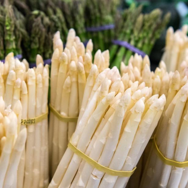 Bündel von weißem und grünem Spargel auf einem Markt.