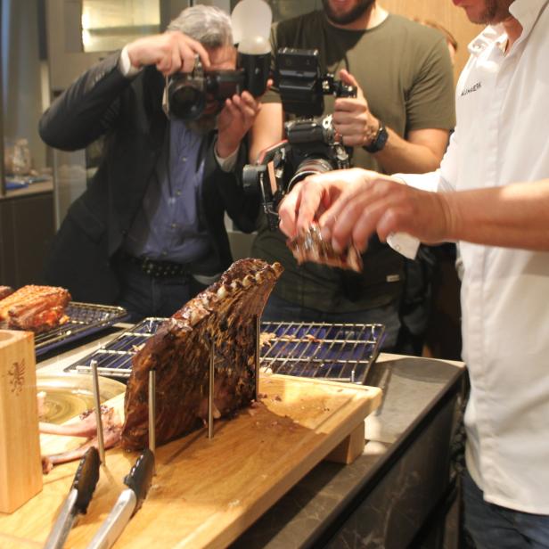 Köche und Fotografen präsentieren und fotografieren ein großes Stück Fleisch.