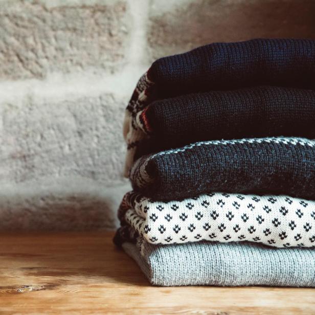 Ein Stapel gestrickter Wollpullover auf einem Holztisch.