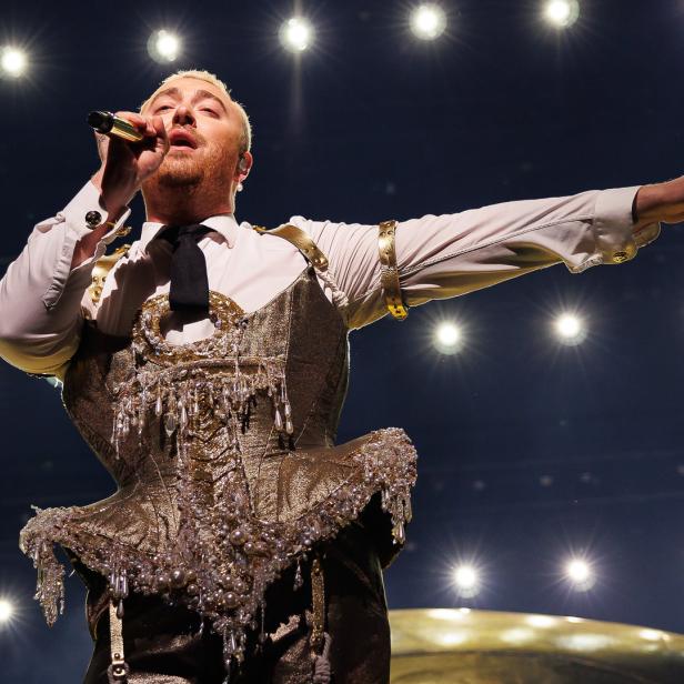 Sam Smith tritt in einem goldenen Korsett und mit Mikrofon auf einer Bühne auf.