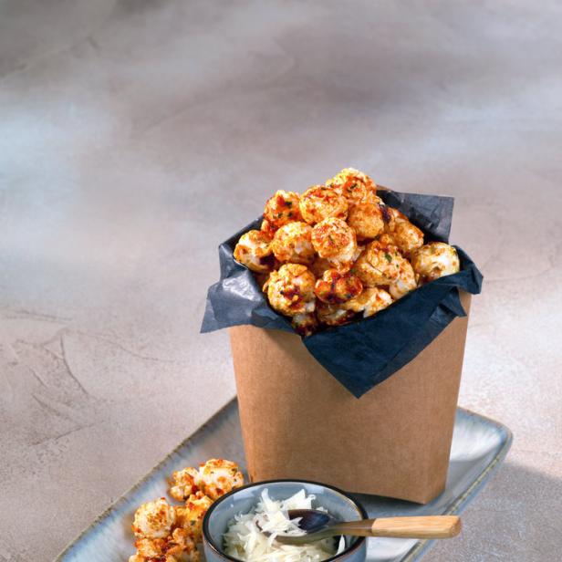 Ein Behälter mit karamellisiertem Popcorn steht neben einer Schale mit Krautsalat auf einem Teller.