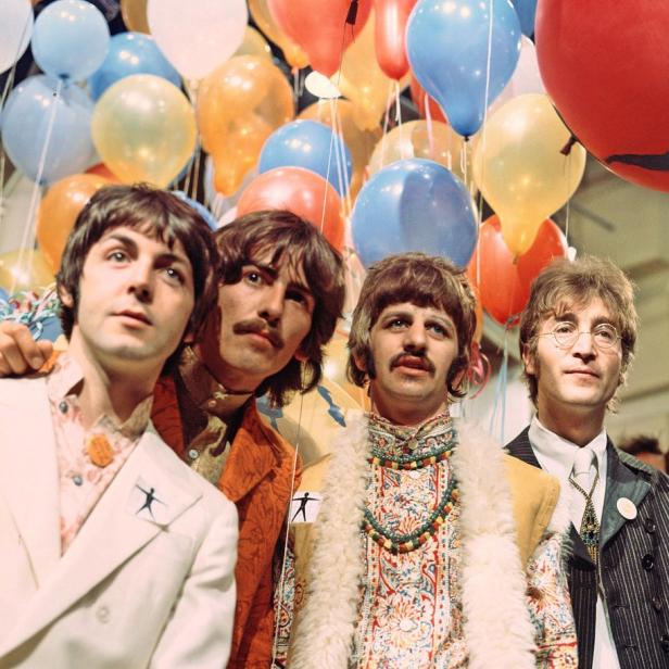 Die Beatles stehen vor einem Hintergrund aus bunten Luftballons.