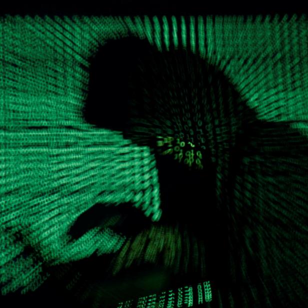 Person mit Kapuze vor Computer, grüner Hintergrund mit Codes.