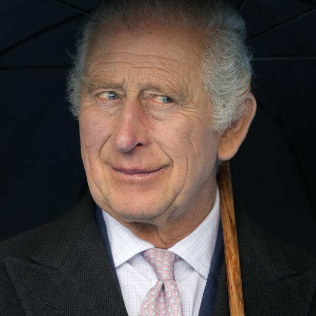 König Charles III. unter einem Regenschirm.