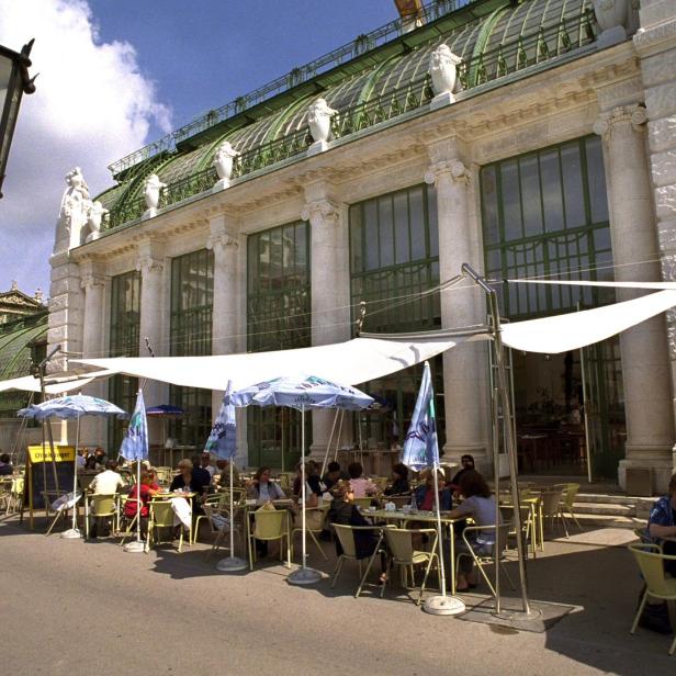 Menschen sitzen im Sommer in einem Strassencafé vor der Hofburg in Wien.