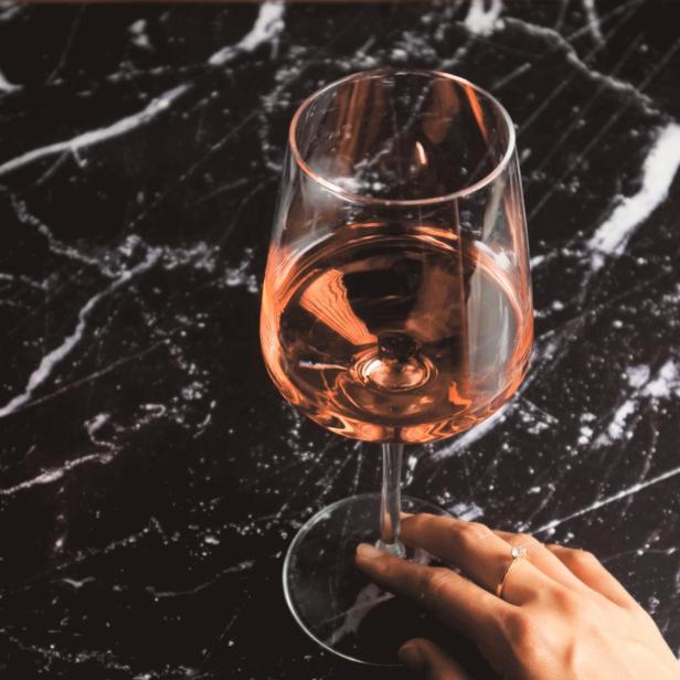 Ein Glas Roséwein steht auf einem schwarzen Marmortisch.