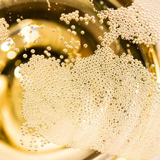 Nahaufnahme von Champagnerblasen in einem Glas.