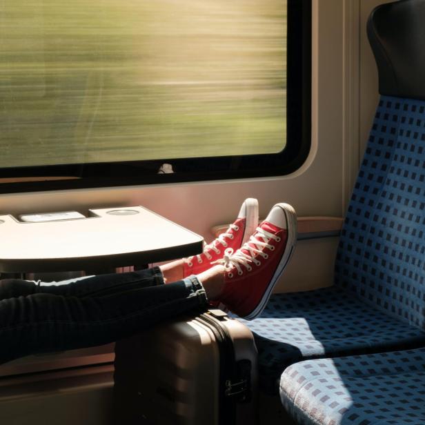 Füße mit Schuhen und ein Koffer in der Deutschen Bahn.