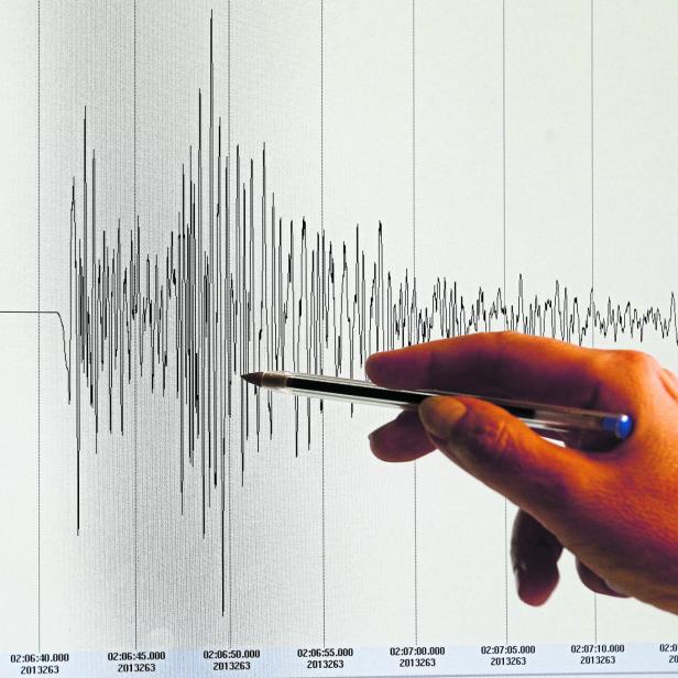 Eine Hand deutet mit einem Stift auf eine seismografische Aufzeichnung eines „Erdbeben in Niederösterreich“.