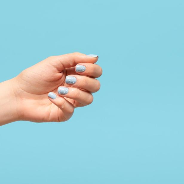 Eine Hand mit hellblau lackierten Fingernägeln vor einem hellblauen Hintergrund.