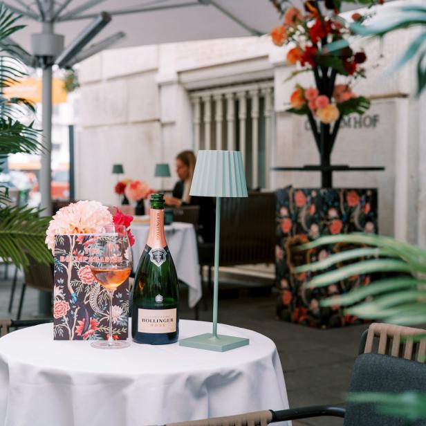 Eine Flasche Bollinger Rosé Champagner und ein Glas auf einem Tisch im Freien.