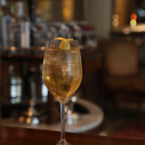 Ein Cocktail mit Eis und Zitronenzeste steht auf einer Bar.