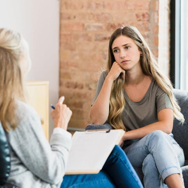 Hopeless teen girl listens to advice from unrecognizable female therapist