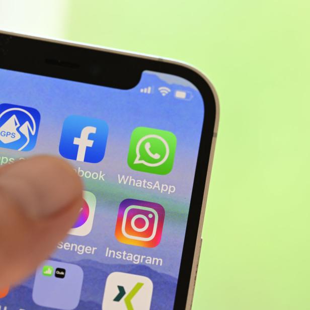 Ein Finger tippt auf dem Bildschirm eines Smartphones mit verschiedenen App-Symbolen wie Facebook und Instagram.
