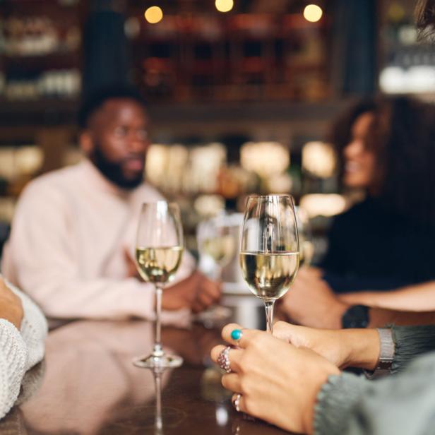 Eine Gruppe von Freunden genießt Weißwein in einem Restaurant.