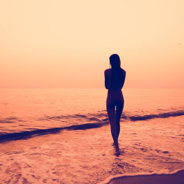 Eine Frau geht am FKK-Strand ins Wasser.