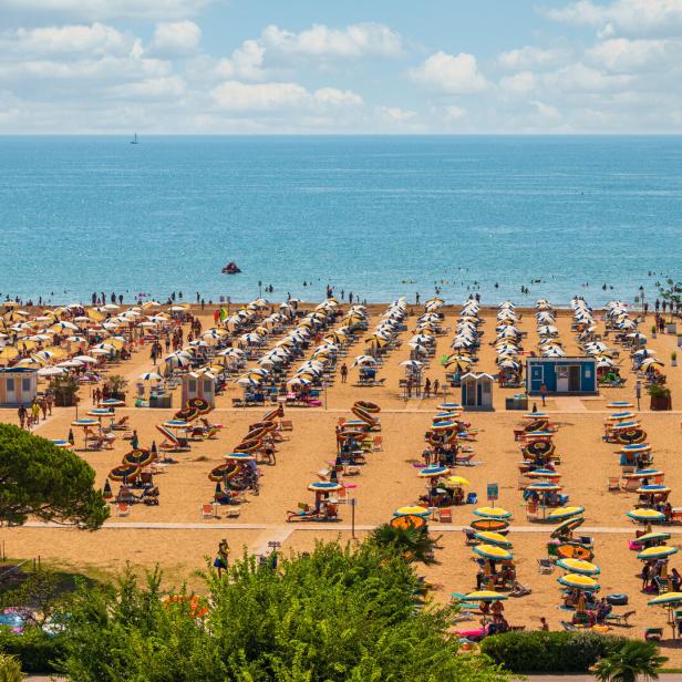Ein voller Strand mit vielen Sonnenschirmen in Bibione.