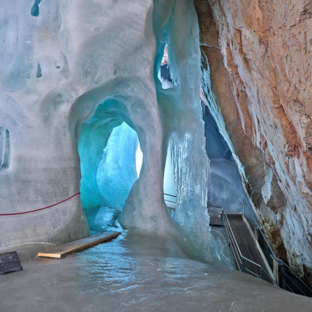 Einblick in eine Eishöhle mit blauem Licht und Eiszapfen.