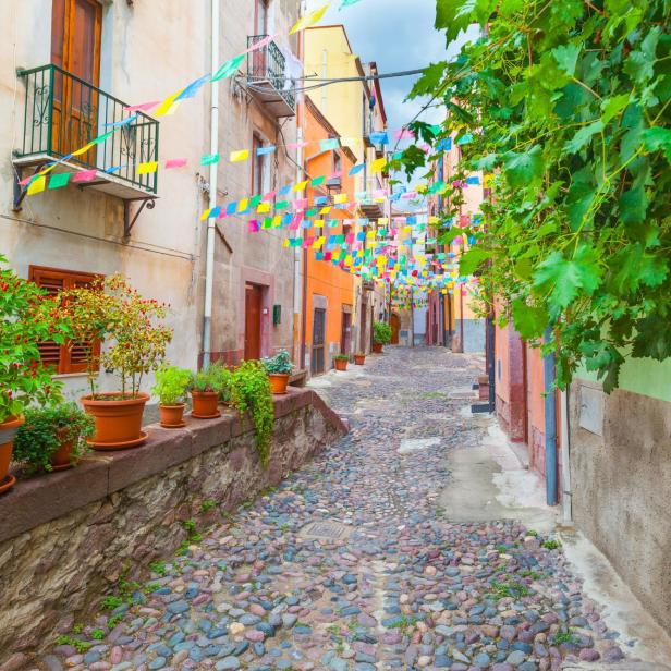 Ein Dorf in Sardinien mit einer Gasse, die mit bunten Wimpeln geschmückt ist.