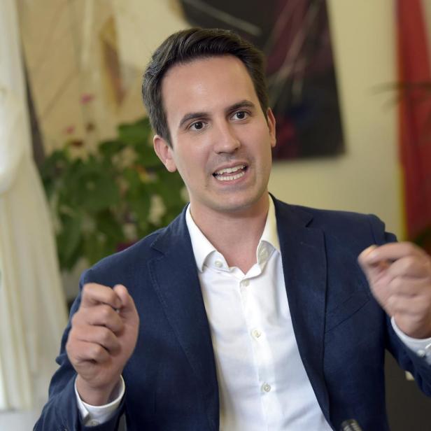 Ein Mann in einem blauen Sakko gestikuliert während eines Gesprächs.