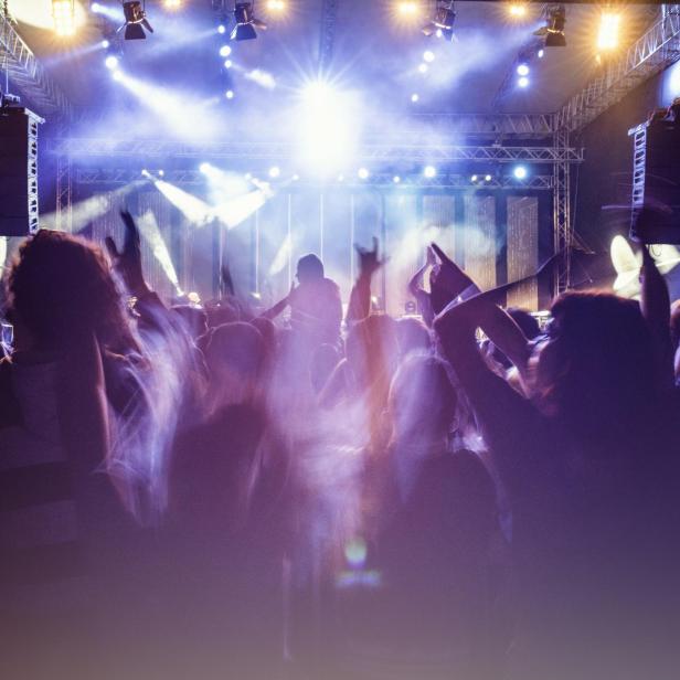 Menschenmenge jubelt bei einem Konzert mit hellen Lichtern.