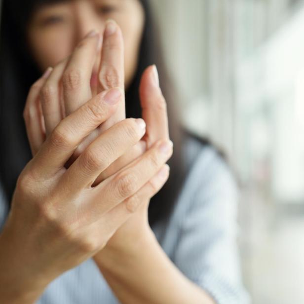 Close-up woman massaging her arthritic hand and wrist, she is suffering from pain and rheumatism.