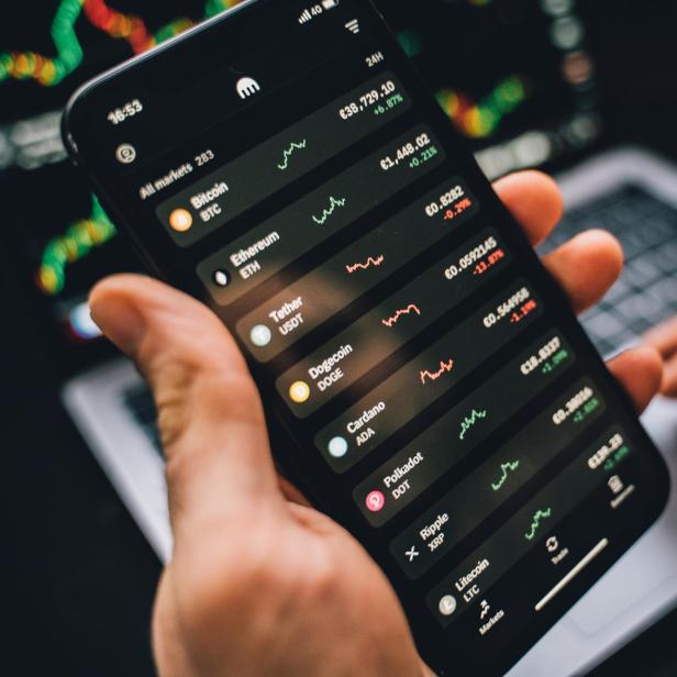 Eine Person betrachtet die Kursentwicklung verschiedener Kryptowährungen auf einem Smartphone.