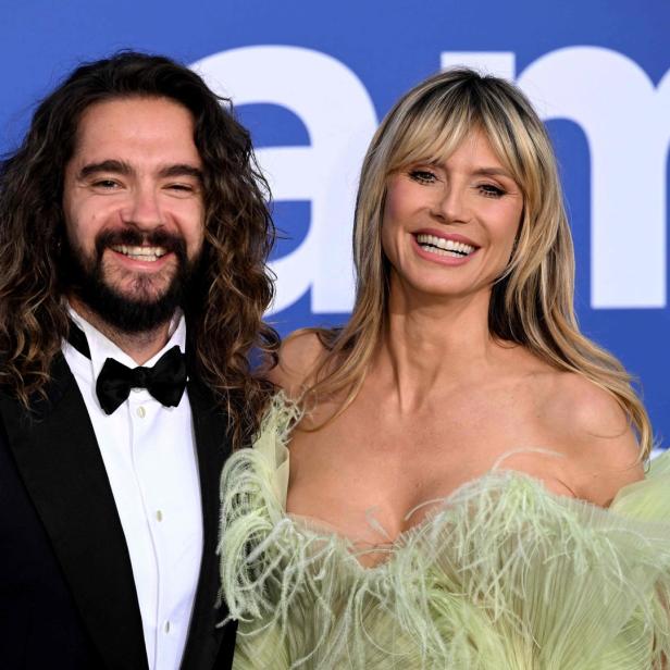 Heidi Klum und Tom Kaulitz posieren lächelnd auf einem roten Teppich.