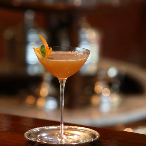 Ein Armagnac-Cocktail wird mit einer Orangenschale garniert serviert.