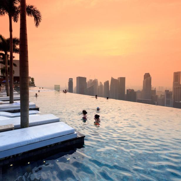 Menschen schwimmen im Pool des Marina Bay Sands Hotels mit Blick auf die Skyline von Singapur.