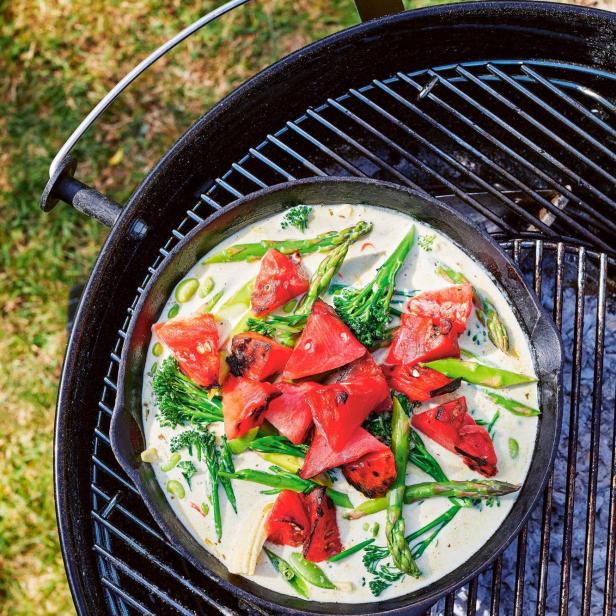 Gegrillte Wassermelone mit Gemüse in einer cremigen Sauce auf einem Grill.
